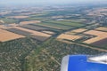 Yellow and green fields, green forest, a small village and a river. View from the airplane window