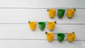 Yellow and green flowerpots hang on the rail.