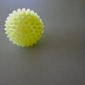 Massage ball, yellow-green with nubs, on gray background