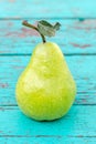 Yellow-green pear on a turquoise surface. Green leaf. Close-up