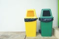 Yellow and Green plastic trash Recycle Bin on the floor and whit