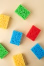 Yellow, green, red, blue sponges on cream colored paper background, copy space, top view, flat lay