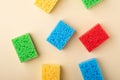 Yellow, green, red, blue sponges on cream colored paper background, copy space, top view, flat lay