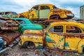 Yellow and green retro cars piled up in a scrapyard. Old damaged cars on the junkyard waiting for recycling