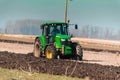 The yellow green tractor makes a deep plowing of the field