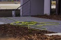 Yellow-green watering hose on the sidewalk, watering plants in the garden, vegetable garden or on the lawn of an apartment Royalty Free Stock Photo