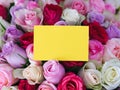A yellow greeting card laying on a bouquet of colorful roses