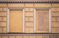 Yellow grey brown scratched shabby stucco wall of an old classic building with walled-up windows background texture Royalty Free Stock Photo