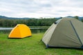 Yellow and grey green tent are set on grass field or meadow near lake with cloudy sky and it look peaceful and quiet place for Royalty Free Stock Photo