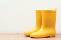 Yellow gumboots on wooden shelf. Yellow rain boots for spring or autumn rainy weather