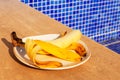 Yellow half peeled banana on the plate on blue ceramic tile mosaic swimming pool background. Fresh organic fruit. Healthy eating Royalty Free Stock Photo