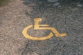 Yellow handicapped symbol of wheelchair painted on asphalt on a parking lot, sign of parking space for disabled visitors. Empty Royalty Free Stock Photo