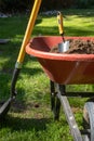 Shovle leaning on a wheelbarrow filled with dirt