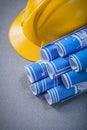 Yellow hard hat blue rolled engineering drawings on grey backgro Royalty Free Stock Photo