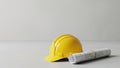 Yellow hard hat and rolled blueprints on white surface in construction setting Royalty Free Stock Photo