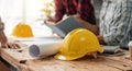 Yellow hard hat on table and house design print design with construction team planning start new project plan in office Royalty Free Stock Photo