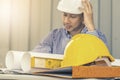 Yellow hard safety helmet hat for safety with engineer team and worker looking paper plans