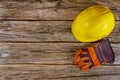 Yellow hard safety wear helmet hat in the construction site leather work gloves in a wood background Royalty Free Stock Photo