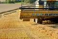 Yellow harvester combine on field harvesting gold wheat Royalty Free Stock Photo