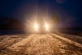 Yellow headlight and dirtroad in the dark after snowing. Car driving on a dangerous road in dire circumstances.