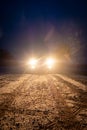 Yellow headlight and dirtroad in the dark after snowing. Car driving on a dangerous road in dire circumstances.