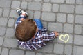 Yellow heart drawn with chalk on asphalt and a little boy next to these drawing. Royalty Free Stock Photo