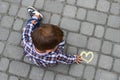 Yellow heart drawn with chalk on asphalt and a little boy next to these drawing. Royalty Free Stock Photo