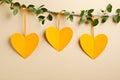 Yellow heart shape garland hanging on beige background. Festive decorated with hearts
