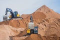 Yellow heavy excavator and bulldozer excavating sand and working during road works, unloading sand and road metal