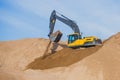 Yellow heavy excavator and bulldozer excavating sand and working during road works, unloading sand and road metal