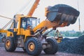 Yellow heavy excavator and bulldozer excavating sand and working during road works, unloading sand and road metal