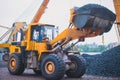 Yellow heavy excavator and bulldozer excavating sand and working during road works, unloading sand and road metal