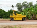 Yellow heavy tractor vibratory roller is driving at construction site