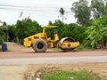 Yellow heavy tractor vibratory roller is driving at construction site