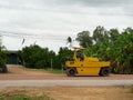 Yellow heavy tractor vibratory roller is driving at construction site