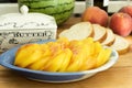 Yellow Heirloom Tomato, Sliced, in a Blue Dish with Bread, Butter Dish, and Peaches Royalty Free Stock Photo