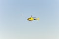 Yellow helicopter flying in the blue sky and the moon next to it during the day.