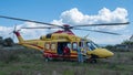 Yellow helicopter rescue operation for patient recovery from assigned ambulance and medical staff equipped for covid 19 Royalty Free Stock Photo