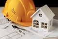 Yellow helmet, mini house and drawing tools on construction plans Royalty Free Stock Photo