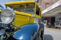 Yellow historic car in close-up view diagonally from the front, with black fenders, side parts with ventilation slots and small wi