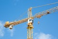 Yellow hoisting crane on blue sky background with clouds Royalty Free Stock Photo