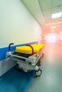 Yellow hospital bed on wheels in wide long modern hall in hospital. Royalty Free Stock Photo