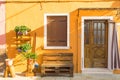 Yellow house with flowers and bench. Colorful houses in Burano island near Venice, Italy. Venice postcard. Famous place for europe