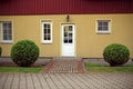 Yellow house front door with red roof and neat bushes Royalty Free Stock Photo