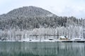 The yellow house on the ice-free lake Ritsa near the mountain forest covered with snow in Abkhazia in winter Royalty Free Stock Photo