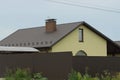 Yellow house with a window under a brown tiled roof and a brick chimney Royalty Free Stock Photo