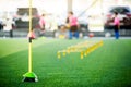 Yellow hurdles and ladder drills on green artificial turf with blurry coach and kid soccer