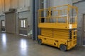 Yellow hydraulic scissor platform stand by for service and maintenance in factory work area.