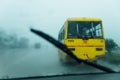 Yellow Indian Bus running in heavy rain that view from inside the car