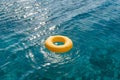 Yellow inflatable ring floating on shimmering blue water under sunlight Royalty Free Stock Photo